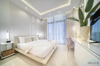 a white bedroom with a bed and a desk at Pleasant Studio Apartment at Azizi Riviera 13, Al Merkadh by Deluxe Holiday Homes in Dubai