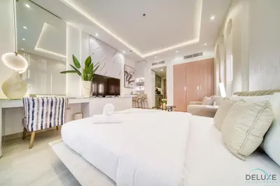 a bedroom with a large white bed and a living room at Pleasant Studio Apartment at Azizi Riviera 13, Al Merkadh by Deluxe Holiday Homes in Dubai