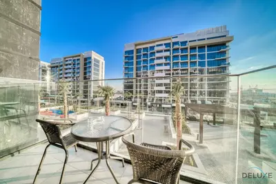 a balcony with a table and chairs and a building at Pleasant Studio Apartment at Azizi Riviera 13, Al Merkadh by Deluxe Holiday Homes in Dubai
