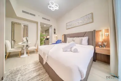 a bedroom with a large white bed and a table at Comfortable Studio Apartment at Azizi Riviera 30, Al Merkadh by Deluxe Holiday Homes in Dubai