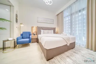 a bedroom with a bed and a blue chair at Comfortable Studio Apartment at Azizi Riviera 30, Al Merkadh by Deluxe Holiday Homes in Dubai