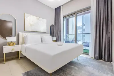 a white bedroom with a large bed and a window at STAY BY LATINEM Luxury 1BR Holiday Home CVR A2403 near Burj Khalifa in Dubai