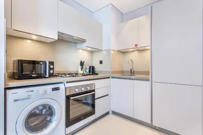 a white kitchen with a washer and a microwave at STAY BY LATINEM Luxury 1BR Holiday Home CVR A2403 near Burj Khalifa in Dubai