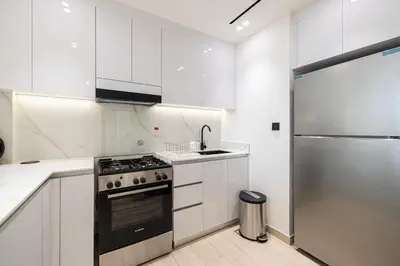 a white kitchen with a stove and a refrigerator at Spacious Balcony, 1BR, Pool, Full Kitchen at JVC in Dubai