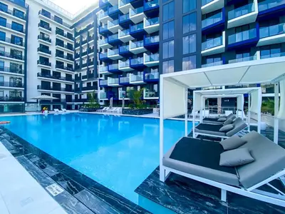a swimming pool with lounge chairs in front of a building at Spacious Balcony, 1BR, Pool, Full Kitchen at JVC in Dubai