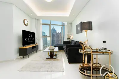 a living room with a black couch and a table at Oraya - Paramount Midtown Luxurious 2BR with Sea View in Dubai