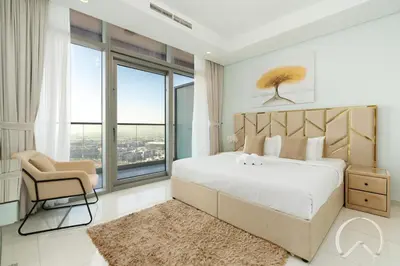 a bedroom with a bed and a chair and windows at Oraya - Paramount Midtown Luxurious 2BR with Sea View in Dubai
