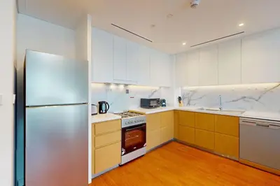 a kitchen with white cabinets and a stainless steel refrigerator at La Vie, JBR - Spacious One Bedroom in Dubai