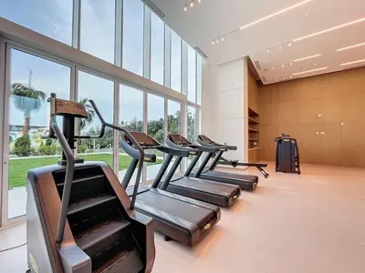 a row of treadmills in a gym with windows at La Vie, JBR - Spacious One Bedroom in Dubai