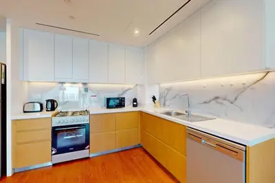a kitchen with white cabinets and a stove and a sink at La Vie, JBR - Spacious One Bedroom in Dubai