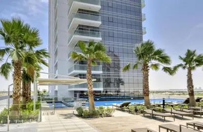 an exterior view of a building with palm trees at Lovely One Bedroom Apartment in Dubai