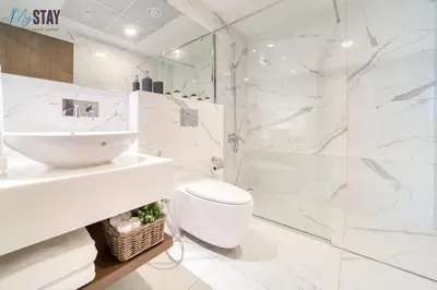 a white bathroom with a toilet and a shower at Luxurious Two-Bedroom Apartment in Dubai