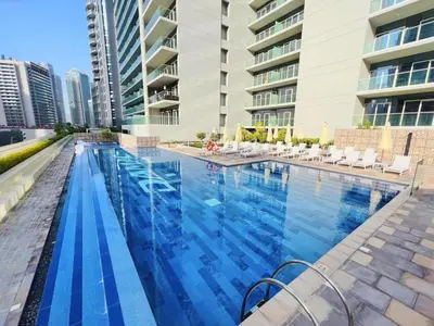 a large swimming pool with chairs and a building at The Dreamer 1BR Burj Khalifa View Business Bay in Dubai