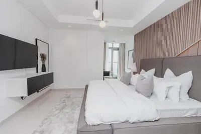 a white bedroom with a large bed and a television at The Cinephile Burj Khalifa View 2BR Dubai in Dubai