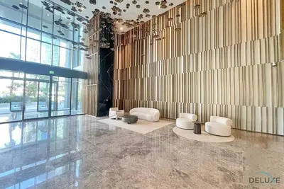 a lobby with white chairs and a wall of windows at Welcoming 1BR Apartment in Ahad Residences Business Bay by Deluxe Holiday Homes in Dubai
