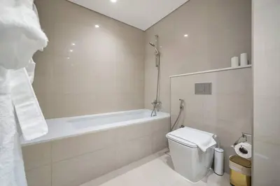 a white bathroom with a tub and a toilet at **Panoramic Views Of Burj Khalifa and Fountain** in Dubai