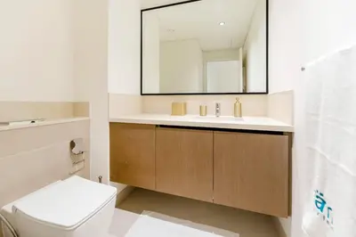 a bathroom with a sink and a toilet and a mirror at FAM Living - Modern 3 Beds+Maidroom Home in Downtown Burj view in Dubai