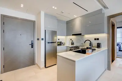 a white kitchen with a sink and a refrigerator at Serene City Stays Binghatti Canal Luxe 2BR in Dubai