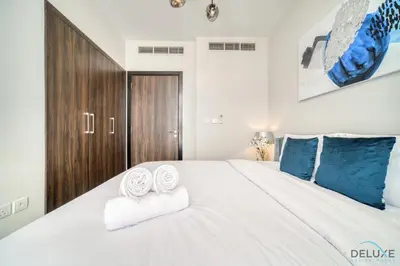 a bedroom with a large white bed with towels on it at Exquisite 4BR Townhouse at DAMAC Hills 2, Dubailand by Deluxe Holiday Homes in Dubai