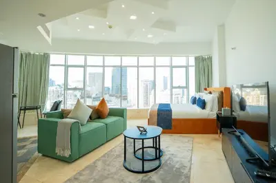 a hotel room with a bed and a green couch at CitiHome - Prime Stylish Studio in Sports City in Dubai