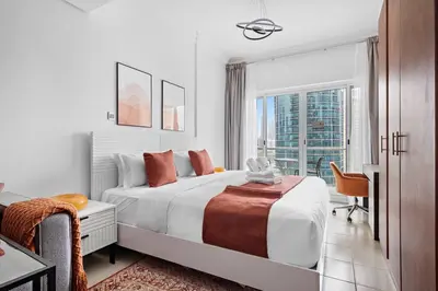 a white bedroom with a bed and a window at StoneTree - Cozy Studio - JLT in Dubai