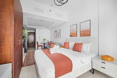 a bedroom with a large white bed with orange pillows at StoneTree - Cozy Studio - JLT in Dubai
