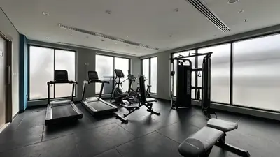 a gym with cardio equipment in a building with windows at EasyGo - Azizi Riviera 9 Bright Studio in Dubai