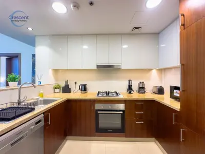 a kitchen with white cabinets and a stove top oven at Burj Vista Burj Khalifa Metro & Mall Access in Dubai