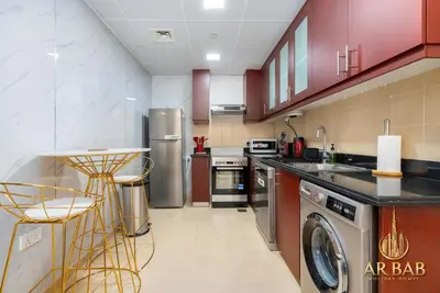 a kitchen with stainless steel appliances and red cabinets at Bahar - Luxury 1BR - Near JBR Beach - Prime Location - JBR in Dubai