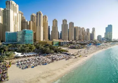 a beach with chairs and umbrellas in front of a city at Bahar - Luxury 1BR - Near JBR Beach - Prime Location - JBR in Dubai