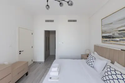 a white bedroom with a bed and a painting on the wall at Fresh & Quiet 1BR at Midtown Noor 4 Tower in Dubai