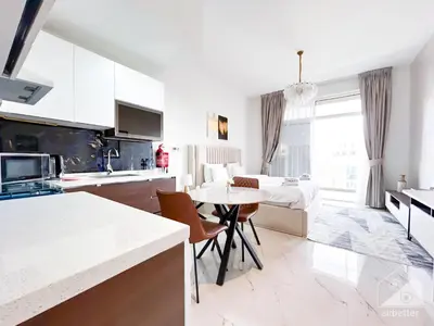 a kitchen and living room with a table and a bed at Stunning studio with Balcony in Arjan in Dubai