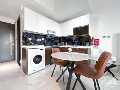 a kitchen with a table and a washing machine at Stunning studio with Balcony in Arjan in Dubai