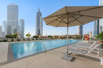 a pool with an umbrella and a chair next to a pool at Silkhaus Comfy 1BR by Burj Khalifa with Balcony in Dubai