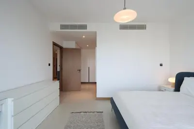 a white bedroom with a bed and a hallway at Livbnb - Modern 3BR with Marina & Sunset View in Dubai