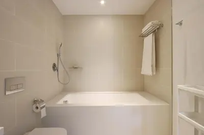 a white bathroom with a tub and a toilet at Livbnb - Modern 3BR with Marina & Sunset View in Dubai