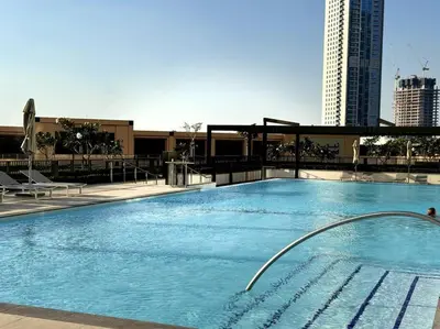 a large blue swimming pool with a tall building at Burj Crown - Luxury Apartment Near Burj Khalifa in Dubai