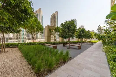 a park with benches and trees and buildings at Maison Privee - Modern Chic Apt with Unobstructed Burj Khalifa Views in Dubai