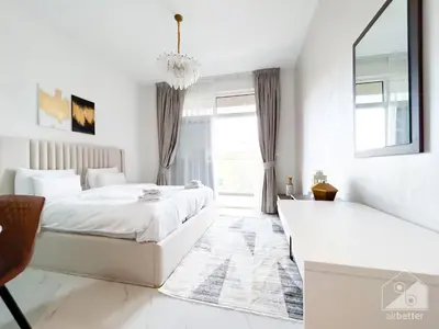 a white bedroom with a bed and a window at Modern & Chic studio with Balcony Dubai in Dubai