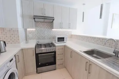 a white kitchen with a stove and a microwave at Modern 1 bedroom at Palm Jumeirah in Dubai