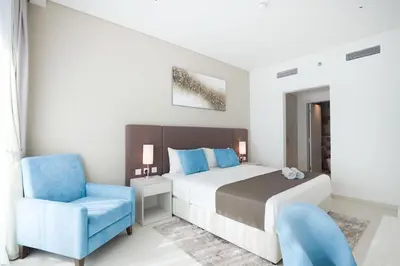 a bedroom with a bed and a blue chair at Modern 1 bedroom at Palm Jumeirah in Dubai