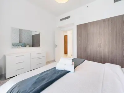 a white bedroom with a large bed and a mirror at Modern Comforts -1 BR in Park Point- Dubai Hills in Dubai