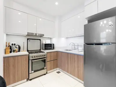 a kitchen with wooden cabinets and a stainless steel refrigerator at Modern Comforts -1 BR in Park Point- Dubai Hills in Dubai