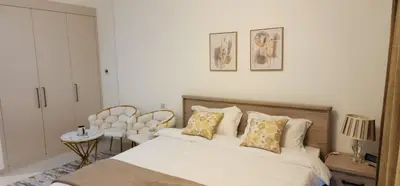 a bedroom with a bed and a table and a chair at Carson Tower C - Damac Hills by Golden Casa in Dubai