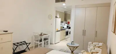 a kitchen and living room with white cabinets and a table at Carson Tower C - Damac Hills by Golden Casa in Dubai