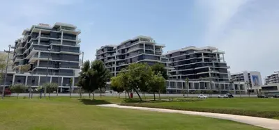 two tall buildings in a city with a park at Carson Tower C - Damac Hills by Golden Casa in Dubai