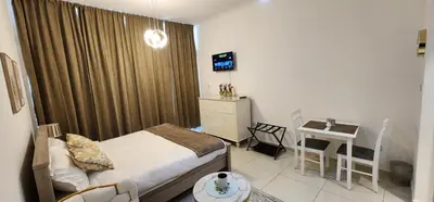 a bedroom with a bed and a table and a desk at Carson Tower C - Damac Hills by Golden Casa in Dubai