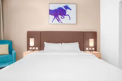 a bedroom with a large bed and a blue chair at The Seven Palm in Dubai