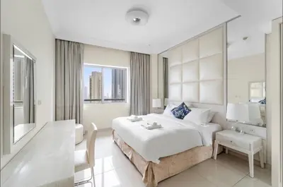 a white bedroom with a large bed and a desk at LUX 1 bed flat with Burj Khalifa View - 3 minute walk to Dubai Mall - Best Location - Best Balcony View in Dubai