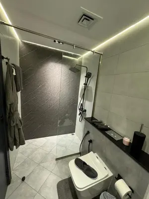 a bathroom with a toilet and a glass shower at Binghatti avenue in Dubai